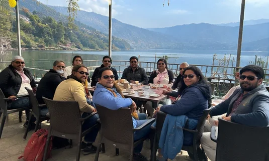 Travellers sharing a meal overlooking Phewa Lake